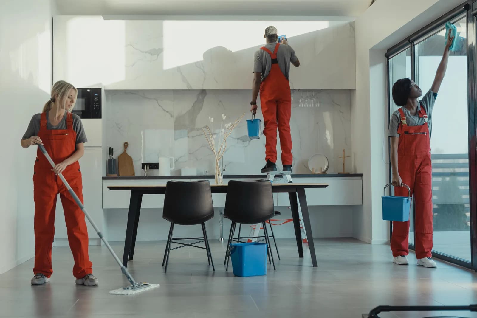 Ekoup cleaning crew mopping the floor and wiping windows in an open-plan office kitchen
